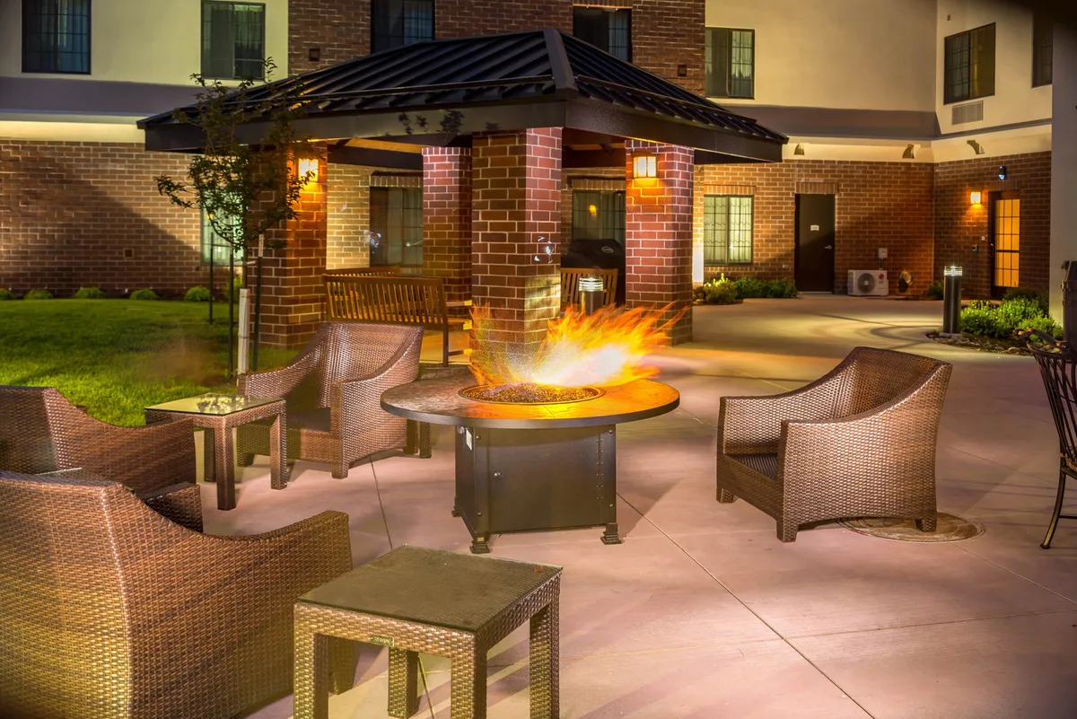 A cozy outdoor BBQ area with a fire pit, wicker chairs, and a gazebo. The setting is perfect for social gatherings, evening relaxation, or classic Colorado cookouts, with an inviting ambiance for guests to enjoy the outdoors together.